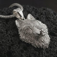 Load image into Gallery viewer, Polished silver wolf head pendant necklace displayed on black volcanic rock, shown in a refined macro product shot with detailed fur texture, alert ears, and intense predatory gaze.