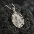 Load image into Gallery viewer, Polished silver Saint Jude pendant necklace on textured volcanic rock, centered macro jewelry photo with detailed Catholic medal engraving and bright silver highlights.