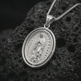 Load image into Gallery viewer, Polished silver Our Lady of Guadalupe spinner pendant necklace on textured volcanic rock, centered macro jewelry photo with detailed Catholic medal engraving and bright silver highlights.