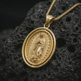 Load image into Gallery viewer, Gold plated Our Lady of Guadalupe spinner pendant necklace on textured volcanic rock, premium close-up studio composition emphasizing the Virgin Mary figure, sunburst rays, and rotating frame design.