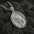 Load image into Gallery viewer, Polished silver Saint Christopher spinning pendant necklace on textured volcanic rock, centered macro jewelry photo with detailed Catholic medal relief and bright silver highlights.