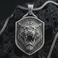 Load image into Gallery viewer, Sterling silver roaring lion shield pendant necklace with an oxidized finish resting on textured volcanic rock, captured in a close-up premium studio composition.