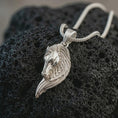 Load image into Gallery viewer, Polished silver Pegasus wing horse pendant necklace displayed on black volcanic rock, shown in a refined macro product shot with elongated horse head, flowing feathered wing detail, and elegant fantasy silhouette.