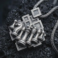 Load image into Gallery viewer, Sterling silver chessboard pendant necklace with an oxidized finish resting on textured volcanic rock, captured in a close-up premium studio composition.