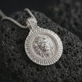 Load image into Gallery viewer, Polished silver Viking lion medallion pendant necklace displayed on black volcanic rock, shown in a refined macro product shot with roaring lion relief, radiant sunburst border, and Othala rune inspired bail detail.