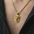 Load image into Gallery viewer, Gold plated ram head shield pendant necklace worn on the neck, captured on a human model in a premium dark-toned lifestyle frame.