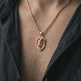 Load image into Gallery viewer, Ram head shield pendant necklace with a rose gold plated finish worn on the neck, shown in a close-up model photograph with a refined symbolic and contemporary appearance.