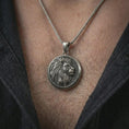 Load image into Gallery viewer, Oxidized lion medallion pendant necklace worn on the neck, styled in a dark lifestyle portrait that emphasizes the noble animal design against the chest.