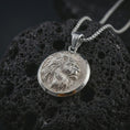 Load image into Gallery viewer, Polished silver lion medallion pendant necklace displayed on black volcanic rock, shown in a refined macro product shot with side profile lion relief, flowing mane detail, and round frame.