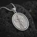 Load image into Gallery viewer, Polished silver Saint Michael spinning pendant necklace on textured volcanic rock, centered macro jewelry photo with detailed archangel relief and bright silver highlights.