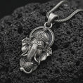 Load image into Gallery viewer, Oxidized Ganesha pendant necklace on textured volcanic rock, close-up studio shot highlighting the elephant god face, ornate crown, tusks, and antique silver contrast.