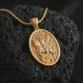 Load image into Gallery viewer, Gold plated Saint George pendant necklace on textured volcanic rock, premium close-up studio composition emphasizing the horse, spear, and defeated dragon symbolism.