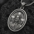 Load image into Gallery viewer, Oxidized spinning Jesus Christ pendant necklace on textured volcanic rock, close-up studio shot highlighting the Jesus portrait, cross halo, oval frame, and antique silver contrast.