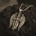 Load image into Gallery viewer, Bronze angel warrior pendant necklace displayed on black volcanic stone, featuring a winged guardian holding a long sword in a bold and detailed sterling silver design.