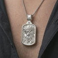 Load image into Gallery viewer, Polished silver crucified Jesus dog tag pendant necklace worn on the chest, masculine lifestyle shot highlighting the side-profile Christ relief, crown of thorns, and bright silver finish.