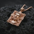 Load image into Gallery viewer, A Jesus crucifix pendant in a rose gold plated finish resting on porous volcanic rock in a premium macro studio shot.