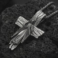 Load image into Gallery viewer, Oxidized Jesus cross pendant necklace on textured volcanic rock, close-up studio shot highlighting the Christ figure, radiant sacred heart, wood texture, and antique silver contrast.