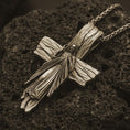 Load image into Gallery viewer, Bronze Jesus cross pendant necklace on textured volcanic rock, close-up studio shot highlighting the Christ figure, radiant sacred heart, wood texture, and antique silver contrast.