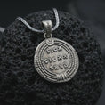 Load image into Gallery viewer, Oxidized Emperor Constans coin pendant necklace resting on black volcanic stone, featuring a Roman imperial profile with Latin inscription in a detailed antique coin-style macro photograph.
