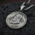 Load image into Gallery viewer, Oxidized heraldic eagle coin pendant necklace resting on black volcanic stone, featuring a round medallion with a crowned double-headed eagle, stars, and laurel branches in a detailed macro product photograph.