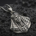 Load image into Gallery viewer, Oxidized Tutankhamun pendant necklace resting on black volcanic stone, featuring the iconic Egyptian pharaoh bust with detailed nemes headdress and cobra crown in a macro product photograph.