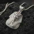 Load image into Gallery viewer, Polished silver Tutankhamun pharaoh pendant necklace displayed on dark volcanic rock, shown in a premium close-up image that highlights the royal bust, long ceremonial beard, and clean ancient Egyptian styling.