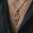 Load image into Gallery viewer, Rose gold plated Skyrim dragon pendant necklace worn on the chest, close-up lifestyle shot featuring the Skyrim-inspired dragon emblem with warm rose gold tones.