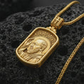 Load image into Gallery viewer, Gold plated Saint Padre Pio dog tag pendant necklace on textured volcanic rock, premium close-up studio composition emphasizing the saint portrait, raised hand, and rectangular medallion design.