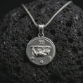Load image into Gallery viewer, Polished silver Emperor Augustus coin pendant necklace displayed on dark volcanic rock, shown in a premium close-up image that highlights the classical emperor portrait and antique Roman coin texture.