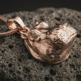 Load image into Gallery viewer, Rose gold plated hippo head pendant necklace on textured volcanic rock, detailed macro product shot with soft warm reflections and bold animal jewelry styling.