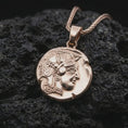 Load image into Gallery viewer, Rose gold plated Athena owl coin pendant necklace presented on textured volcanic stone, showcasing the owl emblem, engraved ancient symbols, and weathered coin-inspired surface in a macro studio shot.