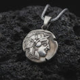 Load image into Gallery viewer, Oxidized Athena owl coin pendant necklace resting on black volcanic stone, featuring an ancient Greek coin-style owl relief with surrounding symbols in a detailed macro product photograph.