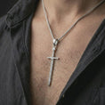 Load image into Gallery viewer, Polished silver medieval sword pendant necklace worn on the chest, masculine lifestyle shot highlighting the long sword silhouette, engraved blade, and bright silver finish.