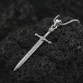 Load image into Gallery viewer, Polished silver medieval sword pendant necklace on textured volcanic rock, centered macro jewelry photo with detailed blade engraving and bright silver highlights.