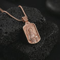 Load image into Gallery viewer, Rose gold plated Saint Francis pendant necklace on textured volcanic rock, detailed macro product shot with soft warm reflections and devotional Saint Francis design.