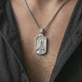 Load image into Gallery viewer, Polished silver Saint Francis pendant necklace worn on the chest, masculine lifestyle shot highlighting the saint relief, bird, wolf detail, and bright silver finish.