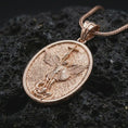 Load image into Gallery viewer, Rose gold plated Saint Michael pendant necklace on textured volcanic rock, detailed macro product shot with soft warm reflections and protective archangel design.