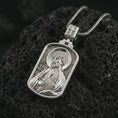 Load image into Gallery viewer, Polished silver Saint James the Apostle pendant necklace on textured volcanic rock, centered macro jewelry photo with detailed Catholic medal engraving and bright silver highlights.