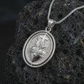 Load image into Gallery viewer, Polished silver Sacred Heart pendant necklace on textured volcanic rock, centered macro jewelry photo with detailed Christian relief and bright silver highlights.