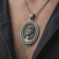 Load image into Gallery viewer, Oxidized spinning Jesus Christ pendant necklace worn on the chest, close-up lifestyle jewelry photo showing the crown of thorns medallion on a spiga chain with dark clothing.