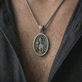 Load image into Gallery viewer, Oxidized Saint Barbara pendant necklace worn on the chest, close-up lifestyle jewelry photo showing the Catholic protection medallion on a spiga chain with dark clothing.
