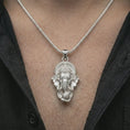 Load image into Gallery viewer, Polished silver Ganesha pendant necklace worn on the chest, masculine lifestyle shot highlighting the elephant god relief, ornate crown, and bright silver finish.