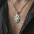 Load image into Gallery viewer, Polished silver Saint Joseph and Jesus pendant necklace worn on the chest, masculine lifestyle shot highlighting the father and child relief, lily detail, sacred heart, and bright silver finish.