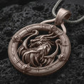 Load image into Gallery viewer, A Bronze dragon pendant rests on dark volcanic rock in a macro studio close-up, showing a fierce mythical creature inside a detailed round frame.