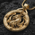 Load image into Gallery viewer, A gold plated dragon pendant lies on textured volcanic rock in a dramatic studio macro shot, highlighting the powerful dragon amulet design.