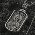 Load image into Gallery viewer, Oxidized Saint Jude dog tag pendant necklace on textured volcanic rock, close-up studio shot highlighting the saint relief, halo, medallion detail, and antique silver contrast.