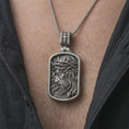 Load image into Gallery viewer, Oxidized crucified Jesus dog tag pendant necklace worn on the chest, close-up lifestyle jewelry photo showing the Christian medallion on a spiga chain with dark clothing.