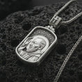 Load image into Gallery viewer, Polished silver Saint Padre Pio dog tag pendant necklace on textured volcanic rock, centered macro jewelry photo with detailed Christian relief and bright silver highlights.