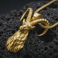 Load image into Gallery viewer, Gold plated ram horn pendant necklace on textured volcanic rock, premium close-up studio composition emphasizing the mythic goat head, spiral horns, and rustic Celtic-inspired design.