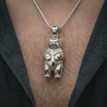 Load image into Gallery viewer, Polished silver baby bear pendant necklace worn on the chest, masculine lifestyle shot highlighting the detailed bear cub form and bright silver finish.